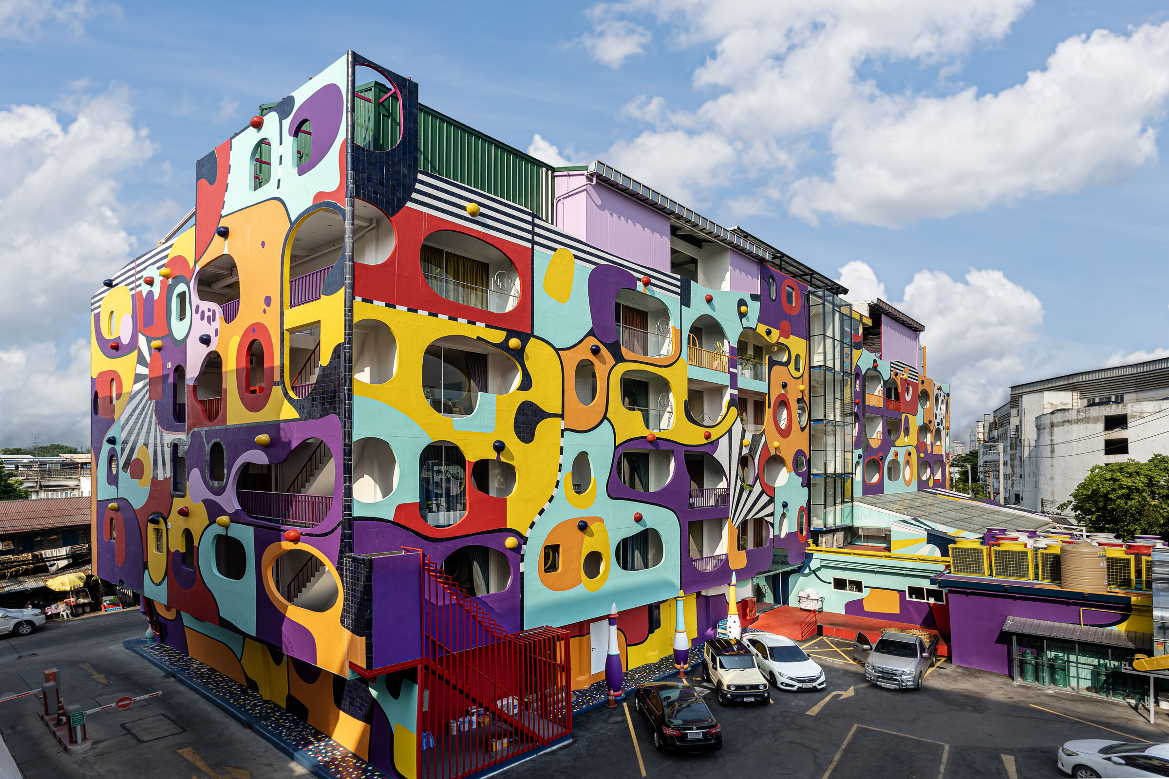 A colour-blocked building with round windows beside a parking lot